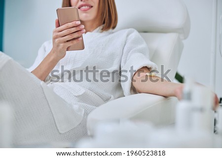 Beautiful Caucasian woman sitting in armchair during medicine procedure in spa salon