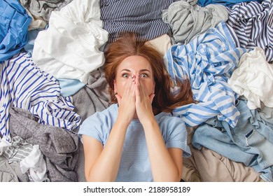 Beautiful Caucasian Woman Smiling And Lying Down With Clutter Clothes On The Floor. Decluttering Pile Of Messy Wardrobe. Cluttered Housewife. Fabric. Shopping. Housework Idea Concept.