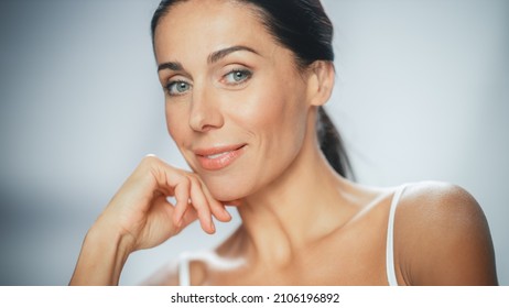 Beautiful Caucasian Woman Touches Her Perfect Face, Smiling. Female Enjoying Her Beauty, High Self Esteem, Wellness. Natural Cosmetic Skincare Products. Medium Portrait with Isolated Background - Powered by Shutterstock