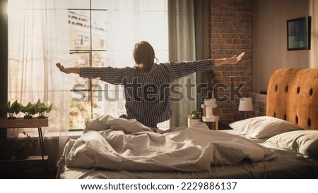 Beautiful Caucasian Woman Waking up in the Morning, Stretches and Gets Out of Bed, Sun Shines From the Apartment Window into Bedroom, She is Ready for Business Opportunities, Adventures. Seize the day