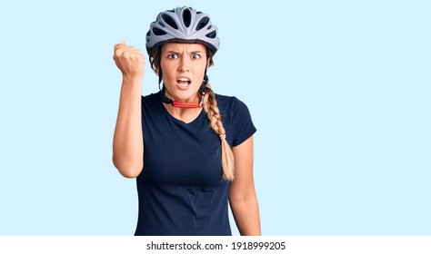 Beautiful caucasian woman wearing bike helmet angry and mad raising fist frustrated and furious while shouting with anger. rage and aggressive concept.  - Shutterstock ID 1918999205