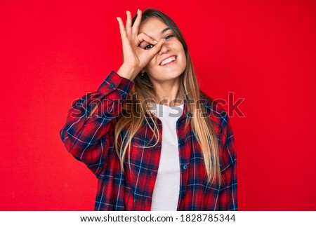 Beautiful caucasian woman wearing casual clothes smiling happy doing ok sign with hand on eye looking through fingers 