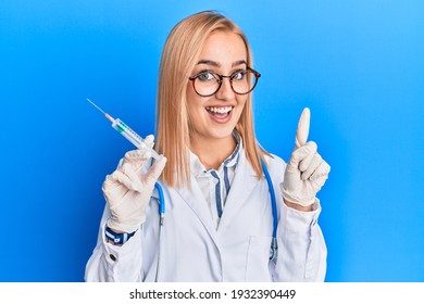 Beautiful caucasian woman wearing doctor stethoscope holding syringe smiling with an idea or question pointing finger with happy face, number one 