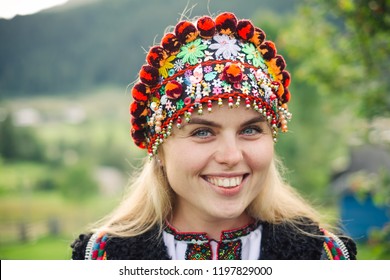 Beautiful caucasian woman wearing ethnic and traditional of the Carpathian mountain Ukrainian clothes. Village background in the autumn.