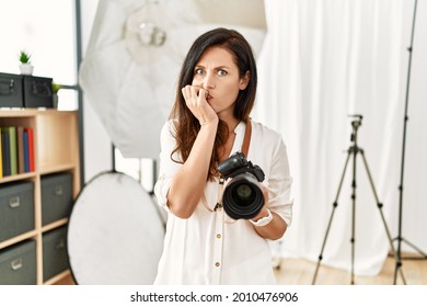 Beautiful Caucasian Woman Working As Photographer At Photography Studio Looking Stressed And Nervous With Hands On Mouth Biting Nails. Anxiety Problem. 