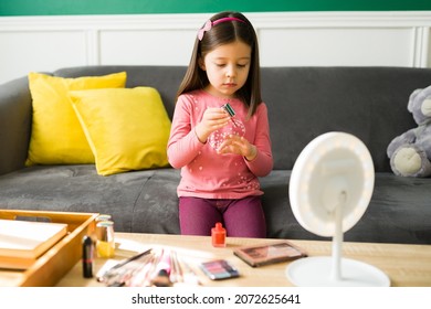 Beautiful Caucasian Young Kid Painting Her Nails With Red Nail Polish And Playing With Her Mom's Makeup 