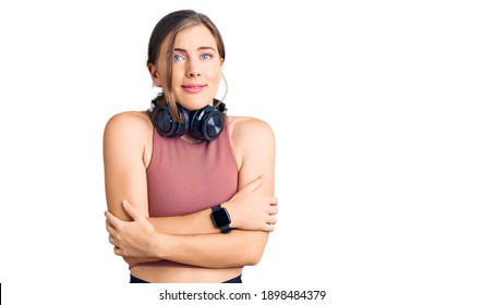 Beautiful Caucasian Young Woman Wearing Gym Clothes And Using Headphones Shaking And Freezing For Winter Cold With Sad And Shock Expression On Face 