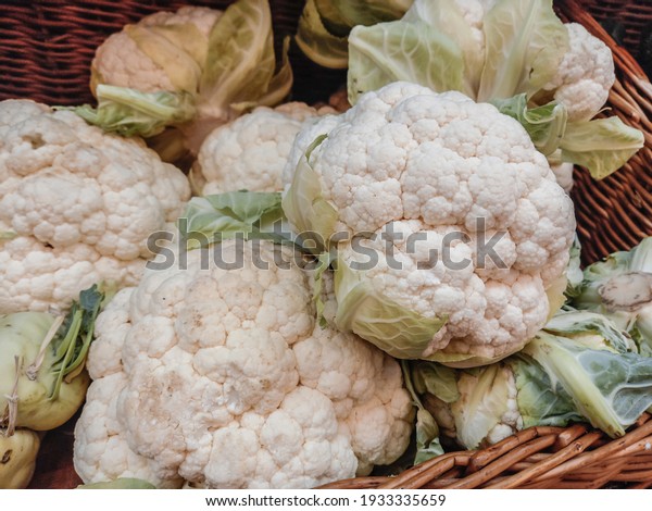 Beautiful cauliflower with green leaves. A\
pile of fresh organic cauliflowers in boxes on a markets, side\
view. New harvest, organic\
vegetables