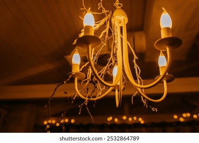 A beautiful chandelier adorned with flickering candles hangs elegantly from the ceiling in a dimly lit, dark room, creating a warm ambiance - Powered by Shutterstock