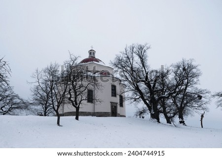 A beautiful chapel on a hill with trees and snow. Landscape with nature in winter. Chapel of the Holy Trinity - Rosice - Czech Republic.