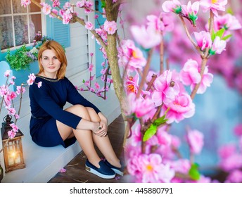 Beautiful Charming Girl In Blue Dress Is Sitting With A Nightlight On The Background Of The Porch At Home With Cherry Blossoms