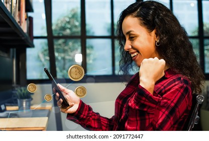 Beautiful cheerful Caucasian woman wearing shirt, holding mobile phone, rasing hand, smiling with happiness and success, invest bitcoin, receiving and win profit. Finance and Investment Concept - Shutterstock ID 2091772447