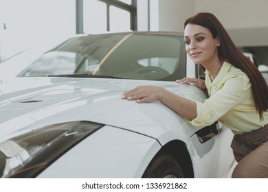 Beautiful Cheerful Dark Haired Elegant Woman Checking Out Stunning White Sportscar At The Dealership. Attractive Female Cusotmer Examining Car On Sale, Copy Space