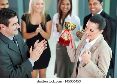 beautiful cheerful female corporate worker receiving a trophy from company CEO