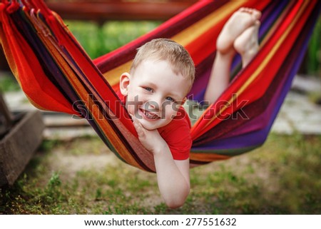 Beautiful cheerful little boy resting in a hammock and having fun. Positive emotions.