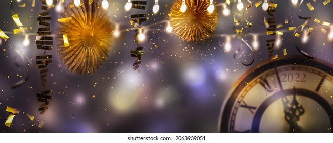 beautiful cheerful party decoration backdrop, new years eve 2022 celebration concept with confetti, streamers and a countdown clock at night, frame from string lights around blurred background