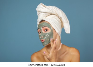 Beautiful Cheerful Teen Girl Applying Facial Clay Mask. Beauty Treatments, Isolated On Blue Background.