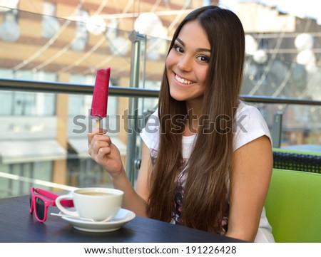 Beautiful cheerful teen girl eating ice-cream in outdoor cafe, urban teenager lifestyle.