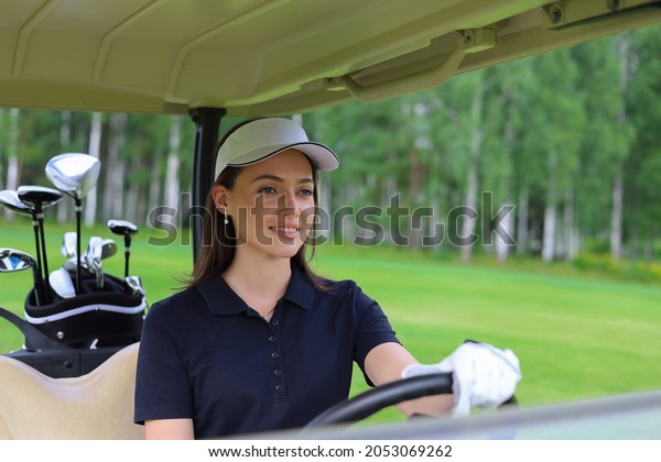 Beautiful cheerful woman\
driving golf cart