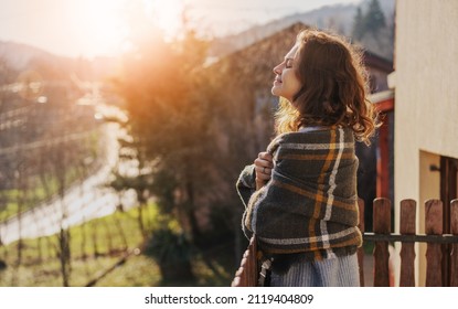 Beautiful cheerful young woman enjoying the sunset and nature with closed eyes on the terrace of a country house - Powered by Shutterstock