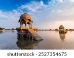 Beautiful Chhatris, dome-shaped pavilions on Gadisar lake or Gadaria lake, an artificial lake once only water source of Jaisalmer city. Blue sky , reflections on water. Jaisalmer, Rajasthan, India.