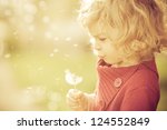 Beautiful child blowing away dandelion flower in spring