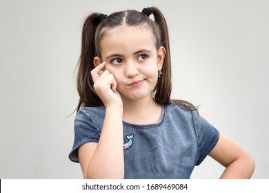Beautiful Child With Brooding Expression  Looking Up With Frown Expressing Misunderstanding. Girl Twisting Mouth Trying To Remember Something. Facial Expressions
