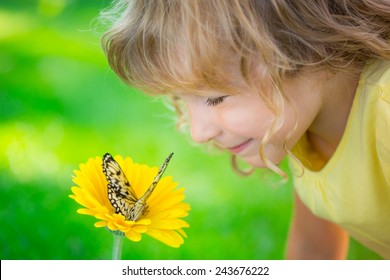 Beautiful child with butterfly in spring park. Happy kid playing outdoors