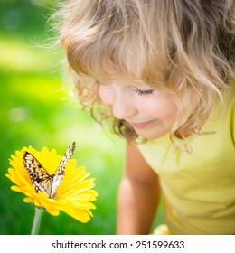Beautiful child with butterfly in spring park. Happy kid playing outdoors