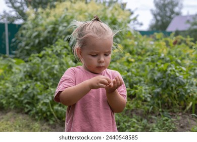 A beautiful child girl enthusiastically examines a small beetle on her palm. The child studies the insect on his small palm with interest. A child looks at a beetle in his hand. - Powered by Shutterstock