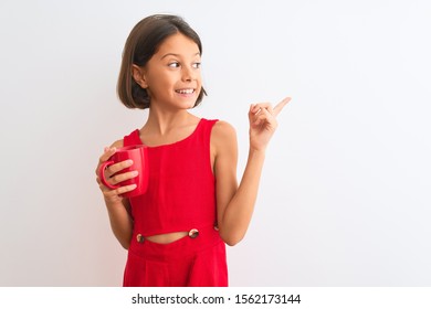 Beautiful Child Girl Holding Red Cup Of Tea Standing Over Isolated White Background Very Happy Pointing With Hand And Finger To The Side