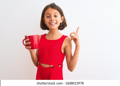 Beautiful Child Girl Holding Red Cup Of Tea Standing Over Isolated White Background Surprised With An Idea Or Question Pointing Finger With Happy Face, Number One