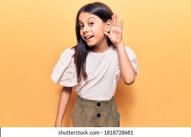 Beautiful Child Girl Wearing Casual Clothes Smiling With Hand Over Ear Listening And Hearing To Rumor Or Gossip. Deafness Concept. 