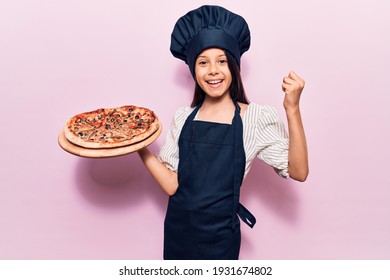 Beautiful Child Girl Wearing Cooker Uniform Holding Italian Pizza Screaming Proud, Celebrating Victory And Success Very Excited With Raised Arms 