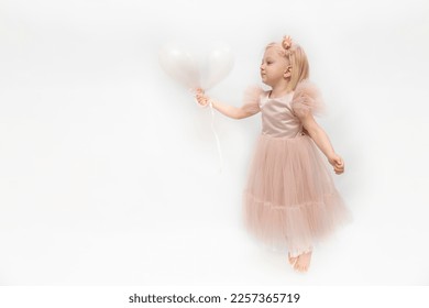 Beautiful child in lush pink dress with tulle skirt holds balloons in hands. Little elegant girl isolated on white background. - Powered by Shutterstock