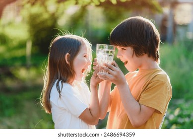 Beautiful children holding a glass of water in their hands on a sunny day. Healthy lifestyle concept - Powered by Shutterstock