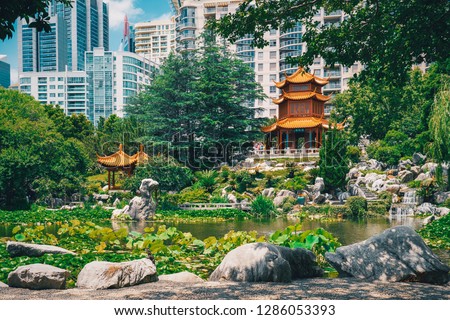 Beautiful Chinese garden and pond surrounding a pagoda contrasted by Sydney city in the background. Chinese Garden of Friendship, Sydney, Australia.