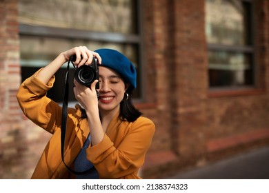 Beautiful Chinese woman with camera. Happy smiling woman taking photos of beautiful location.