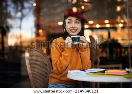 Beautiful Chinese woman drinking coffee in cafe. Young smiling woman enjoy in restaurant