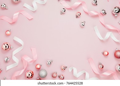 Beautiful Christmas background with shiny balls and ribbons in pastel pink color. Flat lay, top view