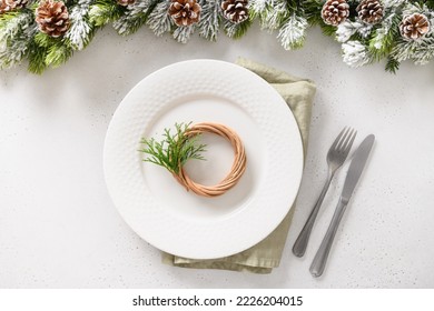 Beautiful Christmas Festive Table Setting With White Plate, Natural Decoration, Pine Cone And Little Wreath On White Table. Xmas Festive Dinner. Top View.