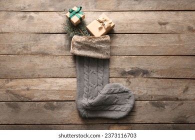 Beautiful Christmas sock with gift boxes and fir branch on wooden background - Powered by Shutterstock