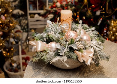 Beautiful Christmas table composition in vase made of fir tree covered with artificial snow, beige balls and bows, candle and beads against the festive interior - Powered by Shutterstock