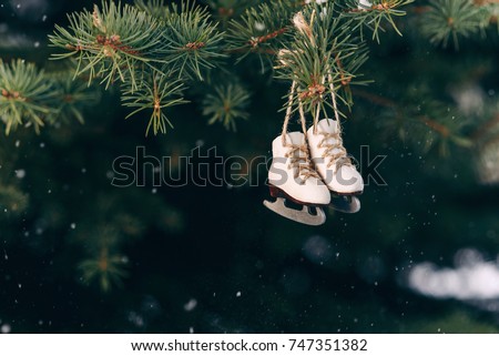 Beautiful christmas tree decoration small ice skates on the rope on a branch.