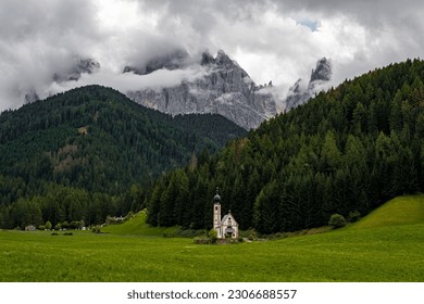 Beautiful Church of St John of Nepomuk (Chiesetta di San Giovanni) in Ranui with a dramatic sky, Val di Funes, Dolomites, Italy