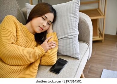 Beautiful clam young asian female relaxes sleeping or taking nap on her comfy couch in minimal living room. resting, afternoon nap concept