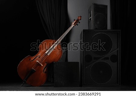 Beautiful classic double bass on the concert stage with acoustic speakers. Acoustic double bass on stage. Contrabass. Wooden musical string instrument.