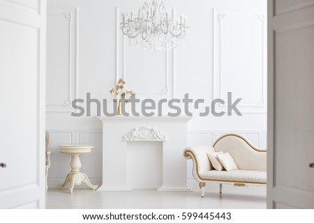 beautiful classical white interior with a fireplace, a sofa and a vintage chandelier. Retro, classics