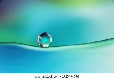 Beautiful clean bright drop of water on smooth surface in blue and turquoise colors, macro. Creative image of beauty of environment and nature.