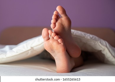 Beautiful Clean Woman's Feet Under Duvet In Bed.